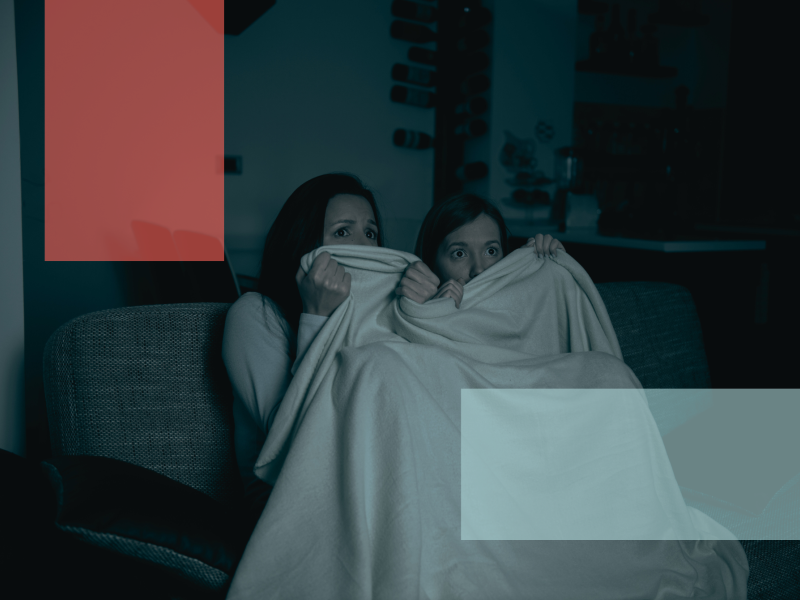 to piger gemmer sig bag tæppe, mens de ser uhyggelig film