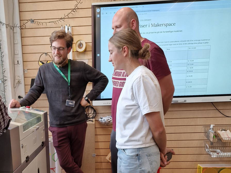 3 personer står ved en lasercutter